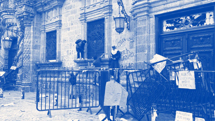 Fachada de un edificio de gobierno con vallas metálicas frente a la entrada