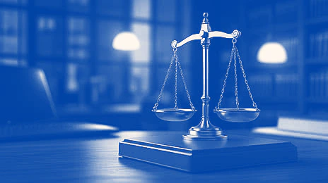 Balanza de la justicia sobre un escritorio de madera frente a una ventana