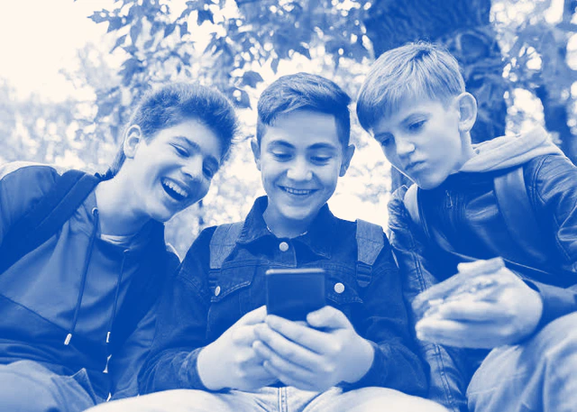 Adolescente mira la pantalla de un teléfono celular con aplicaciones de redes sociales en una habitación